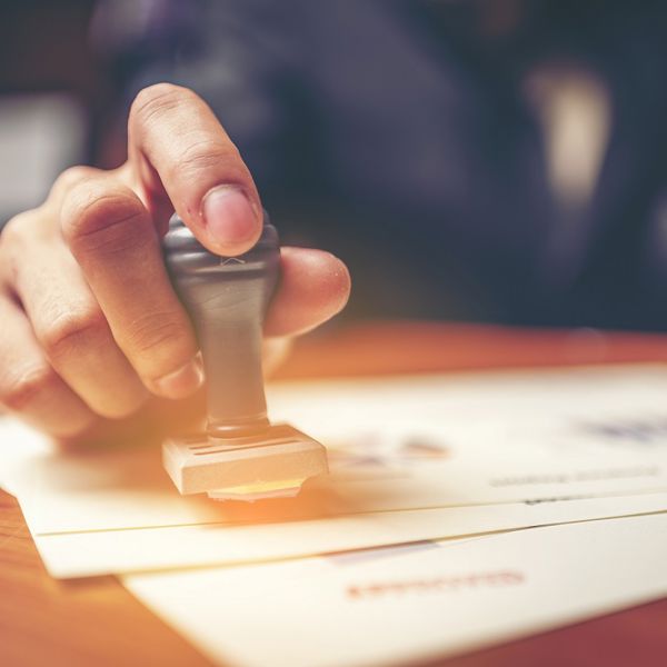 Close-up of a person's hand stamping on certificate document.